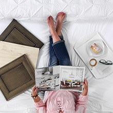 Woman looking at the Diamond brochure with new cabinet finishes next to her